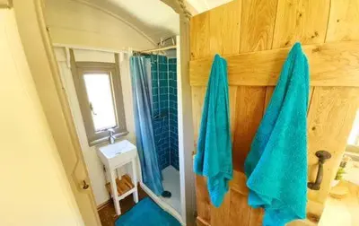 a bathroom with blue towels hanging on a wall at Pen Bryn Shepherd Hut in Hay-on-Wye