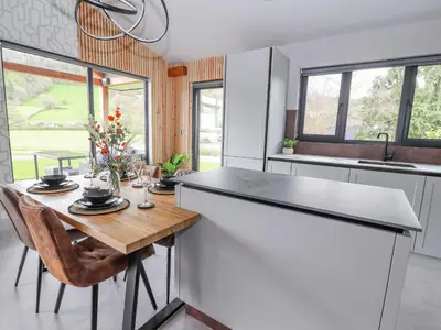 a kitchen with a wooden table and a counter top at Pool View in Meifod