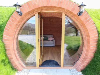 a circular room with a couch in a brick wall at Nant yr Esgair in Machynlleth