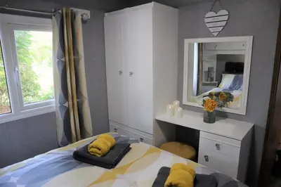 a bedroom with a bed with yellow towels on it at HEDDFAN, Luxury 3 bedroom timber lodge, Now with WiFi, Caer Beris Holiday Park, Builth Wells, SORRY NO TRADESMEN OR CONTRACTORS ALLOWED in Builth Wells