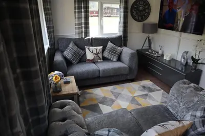 a living room with two couches and a table at HEDDFAN, Luxury 3 bedroom timber lodge, Now with WiFi, Caer Beris Holiday Park, Builth Wells, SORRY NO TRADESMEN OR CONTRACTORS ALLOWED in Builth Wells