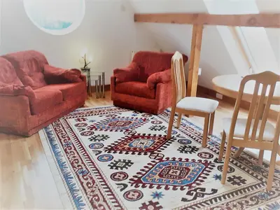 a living room with two chairs and a rug at Topsy-Turvy, Gardeners Cottage, Clungunford, Ludlow, Shropshire SY70PN in Broome