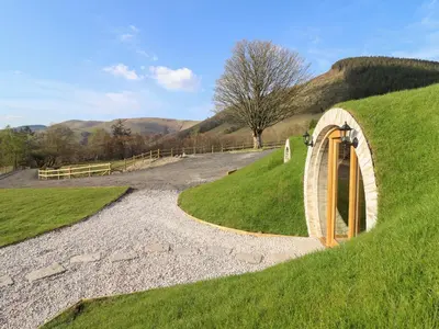 a wooden tunnel on a grassy hill with a path at Nant y Garnedd in Machynlleth