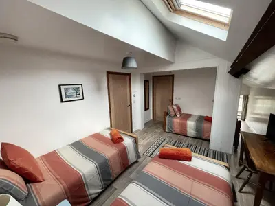 a room with two beds and a table and a window at Converted barn, perfect MTB break, Coed y Brenin in Trawsfynydd