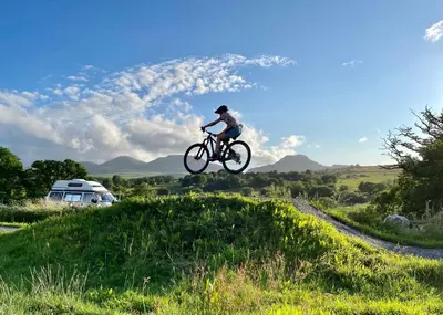 a person jumping a bike over a grassy hill at Converted barn, perfect MTB break, Coed y Brenin in Trawsfynydd