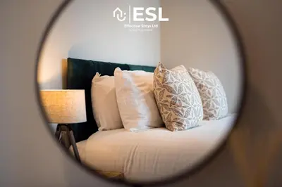 a mirror reflecting a bed with pillows and a lamp at Dashing 2 Bedroom Duplex Apartment, Free Parking in Shrewsbury