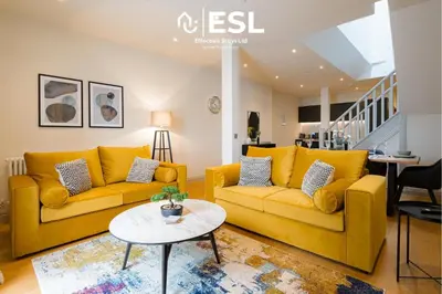 a living room with two yellow couches and a table at Dashing 2 Bedroom Duplex Apartment, Free Parking in Shrewsbury