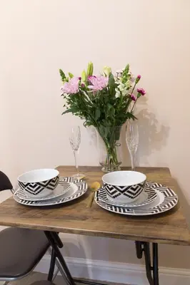 a table with two plates and a vase of flowers at Bridge Hideaway in Llangollen