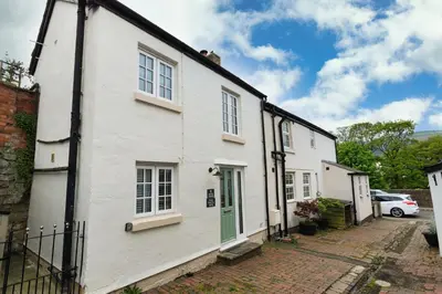 a white house with a green door on a street at Bridge Hideaway in Llangollen
