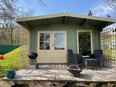 a small green house with a grill and chairs at Ty Bach Twt, Coity Bach in Brecon