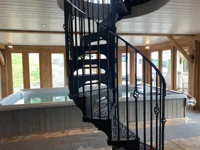 a spiral staircase in a house with a swimming pool at Ty Nofio, Coity Bach in Brecon