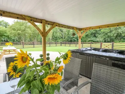 a table with a vase of sunflowers on a patio at Talarddu Cottage in Builth Wells
