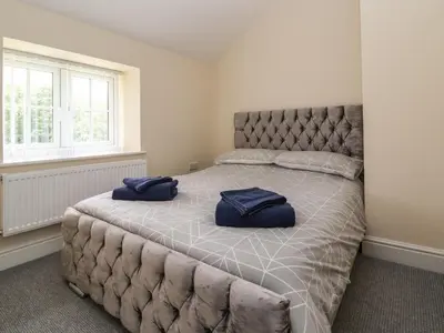 a bedroom with a large bed with blue pillows on it at Cae Iocyn in Wrexham