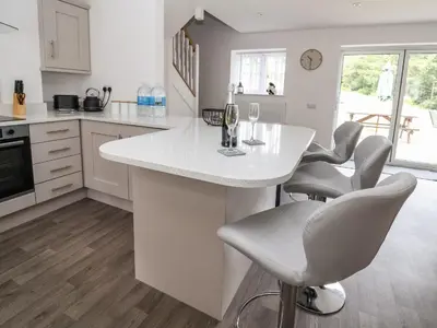 a kitchen with a white island with bar chairs at Cae Iocyn in Wrexham