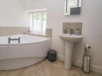a white bathroom with a tub and a sink at Cae Iocyn in Wrexham