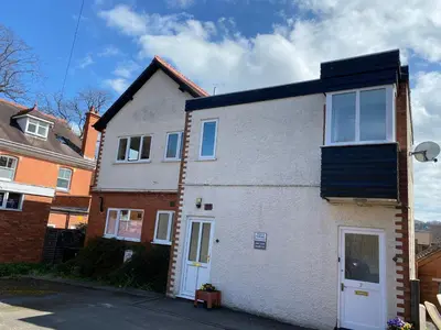a white house with a black roof on a street at Large Ground floor apartment in the heart of Church Stretton with free parking in Church Stretton