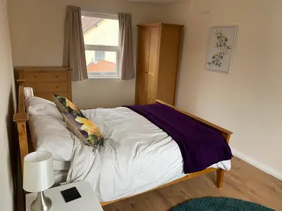 a bedroom with a bed with white sheets and a window at Spacious first floor apartment in the centre of Church Stretton with free parking in Church Stretton