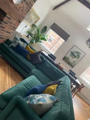 a living room with a green couch with pillows at The Old Fire Station Ludlow in Ludlow