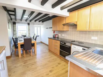a kitchen with a table and a dining room at Tan Y Capel in Llanbrynmair