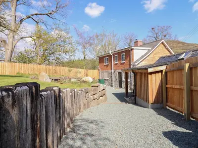 a wooden fence next to a house with a gate at Tan Y Capel in Llanbrynmair