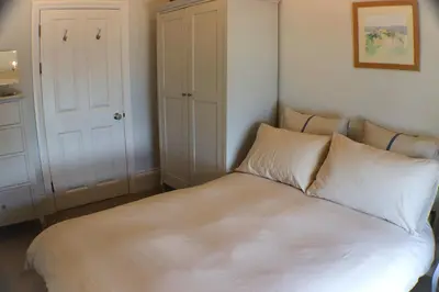 a bed with white sheets and pillows in a room at Seaside Apartment in Aberystwyth