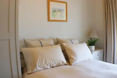 a bed with white pillows and a picture on the wall at Seaside Apartment in Aberystwyth