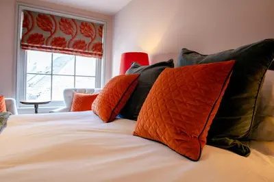 a bed with black and orange pillows and a window at RHUBARB at Drapers Hall in Shrewsbury