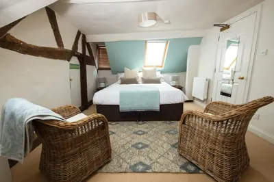 a bedroom with a bed and two wicker chairs at RHUBARB at Drapers Hall in Shrewsbury