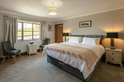 a bedroom with a bed and a chair and a window at Beaconsview B&B in Brecon