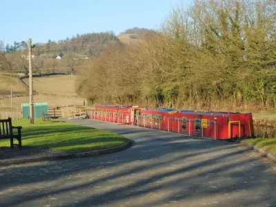 a small train traveling down a road next to a street at Wrens Nest in Llanfair Caereinion