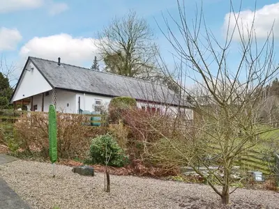 a white house with a green sign in front of it at Blackbird Cottage in Llanfair Caereinion
