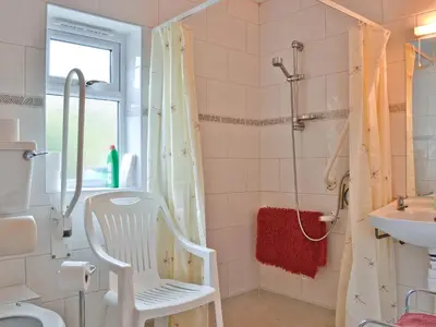 a bathroom with a white chair and a shower at Blackbird Cottage in Llanfair Caereinion