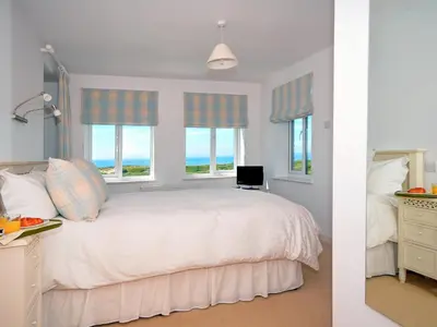 a bedroom with a white bed and two windows at Tir Gafr in Harlech