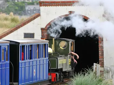 a steam engine train coming out of a tunnel at Gors Y Gader in Llanelltyd