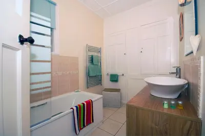 a white bathroom with a tub and a sink at Seascape in New Quay