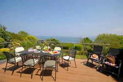 a table and chairs sitting on a deck with a table and a grill at Seascape in New Quay
