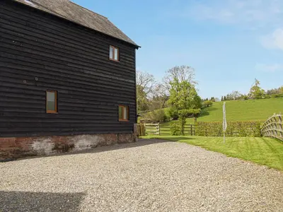 a black barn with a gravel road next to it at The Granary in Kingsland