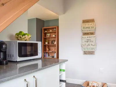 a kitchen with a microwave and a shelf with apples at Little Bank Cottage in Lane to Richards Castle