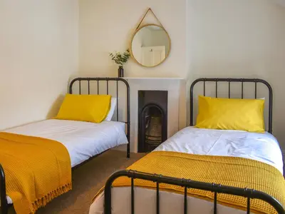 two beds with yellow pillows in a room with a mirror at Ty Ni in Bala