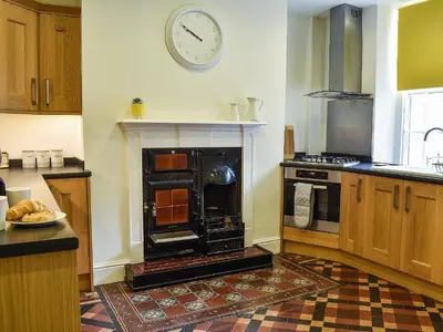 a kitchen with a stove and a clock on the wall at Ty Ni in Bala