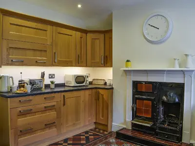 a kitchen with wooden cabinets and a clock on the wall at Ty Ni in Bala