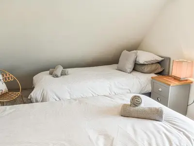 a room with two beds and a table with a lamp at Bryn Derwen in Harlech