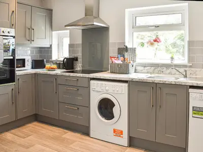 a kitchen with a washer and dryer on a counter at Bryn Derwen in Harlech