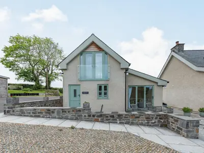 a house with a glass door and stone steps at The Old Cow Shed At Ty Hir in Cilcennin