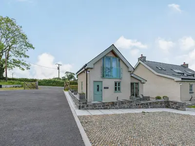 a white house with a blue door on a driveway at The Old Cow Shed At Ty Hir in Cilcennin