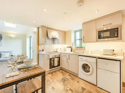 a kitchen with white cabinets and a washer and dryer at The Old Cow Shed At Ty Hir in Cilcennin