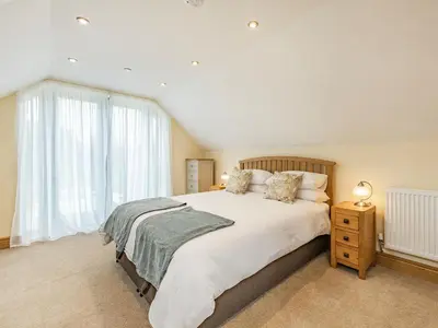 a bedroom with a large bed and a window at The Old Cow Shed At Ty Hir in Cilcennin