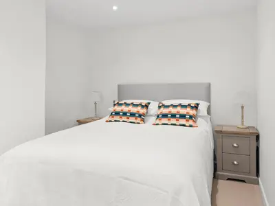 a white bed with two pillows and a night stand at Croft Y Beudy in Henfynyw Upper