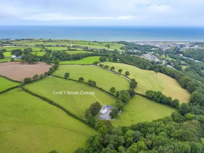 an aerial view of a field with trees and the ocean at Croft Y Beudy in Henfynyw Upper