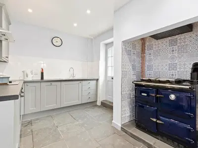 a kitchen with white cabinets and a blue island at Croft Y Beudy in Henfynyw Upper